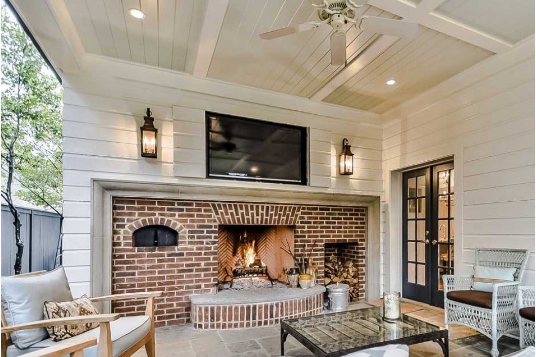 Covered porch with fireplace and seating by Hopedale Builders in Charlotte, NC